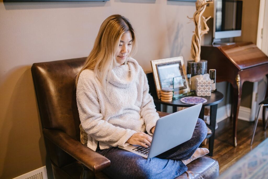 Mastering the First Impression: Your intriguing post title goes here Woman seated on a chair using a laptop, enjoying a cozy home office environment.